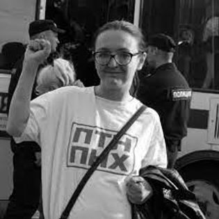 Photo en noir et blanc montrant Yelena Grigorieva brandissant de manière douce son poing gauche. Elle sourit à la caméra. 